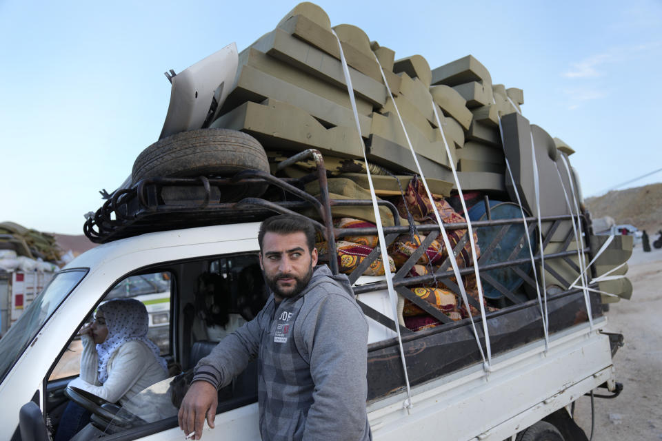 A Syrian refugee man stands outside his pickup which is full of belongings, as he waits at a gathering point to cross the border back home to Syria, in the eastern Lebanese border town of Arsal, Lebanon, Wednesday, Oct. 26, 2022. Several hundred Syrian refugees boarded a convoy of trucks laden with mattresses, water and fuel tanks, bicycles – and, in one case, a goat – Wednesday morning in the remote Lebanese mountain town of Arsal in preparation to return back across the nearby border.(AP Photo/Hussein Malla)