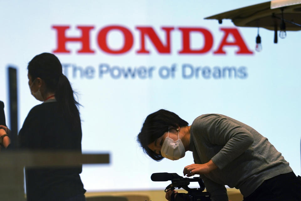 A woman wearing a protective mask to help curb the spread of the coronavirus works near the logo of Honda Motor Company at a showroom Thursday, May 13, 2021, in Tokyo. Honda swung into the black in January-March, recording a 213 billion yen ($2 billion) profit, despite the ongoing uncertainties unleashed by the coronavirus pandemic, the results, released Friday, May 14, 2021. (AP Photo/Eugene Hoshiko)