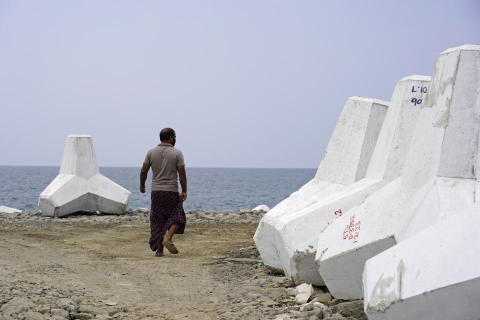 Esidor Rajan walks near tetrapods that will be part of a new sea wall in the Chellanam area of Kochi, Kerala state, India, Feb. 28, 2023. Tens of millions of people in India live along coastlines and thus are exposed to major weather events. One common adaptation technique, in India and other countries hit hard by rising seas and oceanic storms, is to build sea walls. (AP Photo)