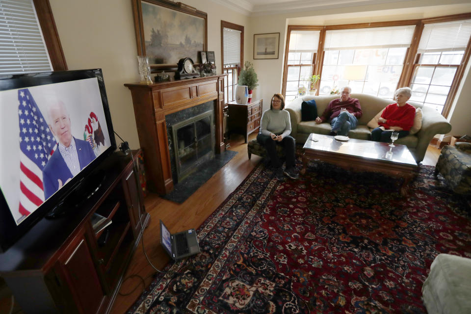 Lally Doerrer, left, and neighbors Douglas and Marlene Groll, watch Joe Biden during his Illinois virtual town hall, in her living room Friday, March 13, 2020, in Chicago. (AP Photo/Charles Rex Arbogast)