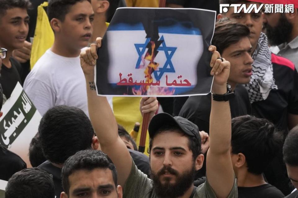 真主黨的支持者高舉被撕毀、燃燒的以色列國旗，象徵會與以國奮戰到底。（圖／AP美聯社)