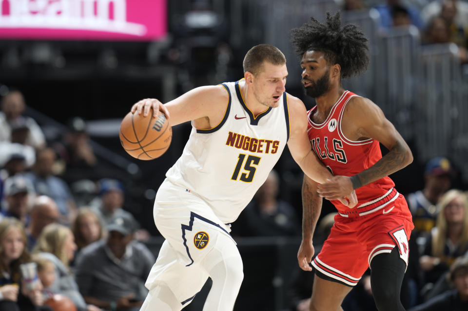 Denver Nuggets center Nikola Jokic, left, drives to the rim as Chicago Bulls guard Coby white defends in the first half of a preseason NBA basketball game Sunday, Oct. 15, 2023, in Denver. (AP Photo/David Zalubowski)