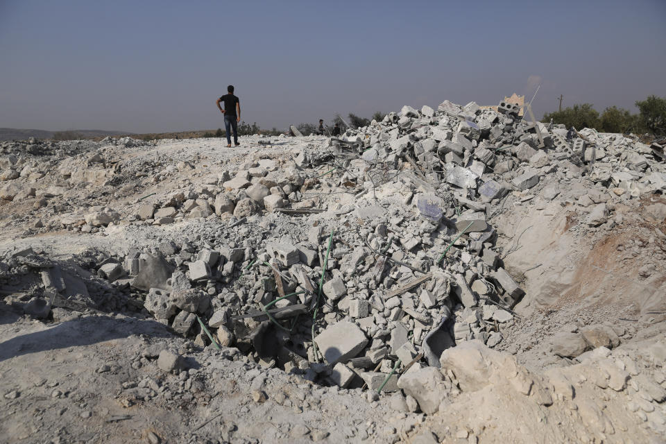 People look at a destroyed houses near the village of Barisha, in Idlib province, Syria, Sunday, Oct. 27, 2019, after an operation by the U.S. military which targeted Abu Bakr al-Baghdadi, the shadowy leader of the Islamic State group. President Donald Trump says Abu Bakr al-Baghdadi is dead after a U.S. military operation in Syria targeted the Islamic State group leader. (AP Photo/Ghaith Alsayed)