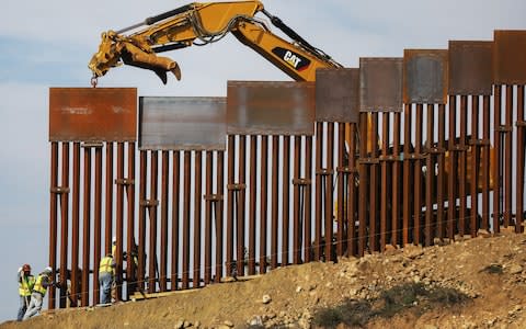 A construction crew installs new sections of the U.S.-Mexico border barrier replacing smaller fences  - Credit: Getty