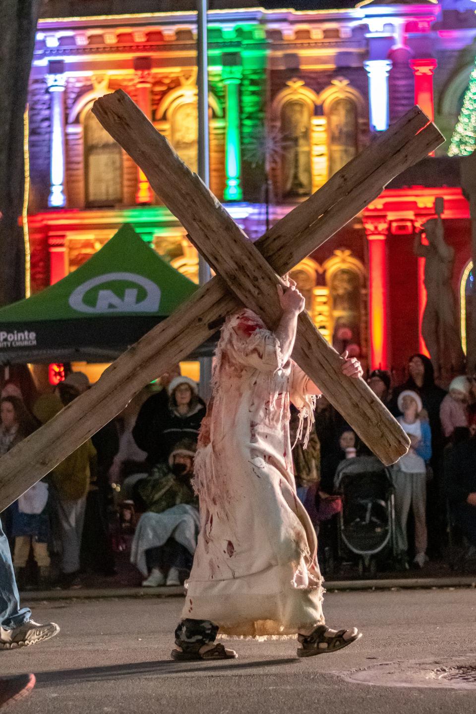 The Living Word Outdoor Drama participates in the 2023 Cambridge Christmas Parade, with an actor portraying Christ carrying a giant cross up Wheeling Avenue.