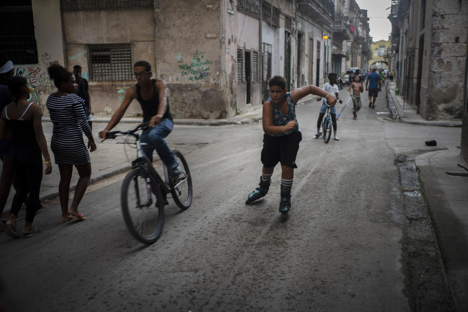 In this Nov. 9, 2019 photo, a youth rollerblades amid cyclists and pedestrians in Old Havana, Cuba. The city will celebrate its 500th anniversary on Nov. 16. (AP Photo/Ramon Espinosa)