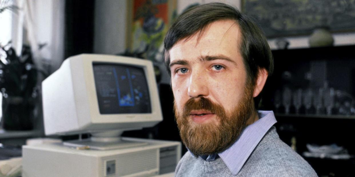alexey pajitnov, wearing a blue gray sweater, looks directly into the camera while sitting at a desk, with a computer in the background