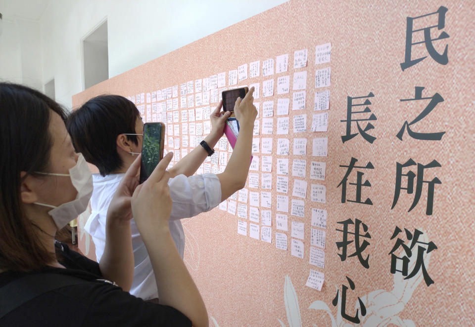 People take photos of a message wall to the late former President Lee Teng-hui with Lee's quote ''The desire of the people is in my heart'' at the memorial venue in Taipei, Taiwan, Saturday, Aug. 1, 2020. Lee, who brought direct elections and other democratic changes to the self-governed island despite missile launches and other fierce saber-rattling by China, died on Thursday at age 97. (AP Photo/Chiang Ying-ying)