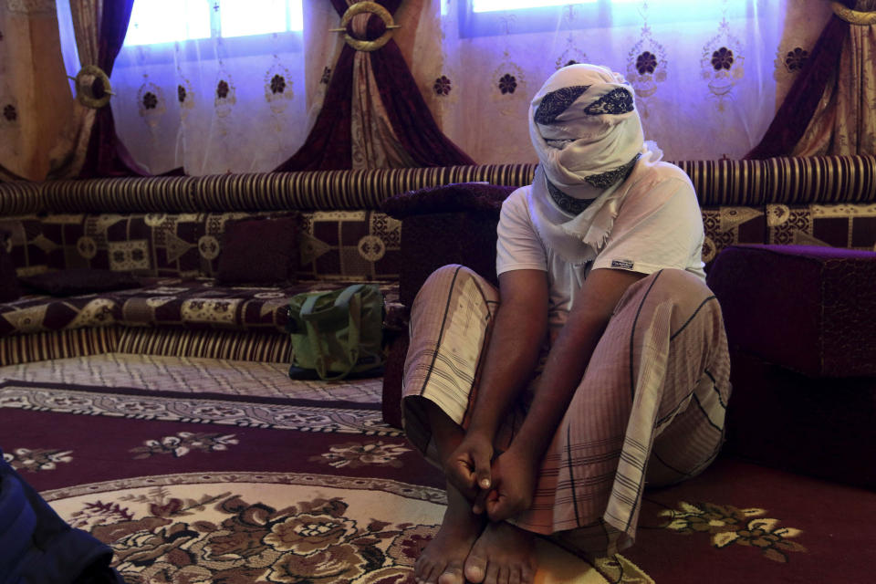 FILE - In this May 11, 2017 file photo, a former detainee covers his face for fear of being detained again, as he shows how he was kept in handcuffs and leg shackles while held in a secret prison at Riyan airport in the Yemeni city of Mukalla, in Aden, Yemen. On Tuesday, June 30, 2020, the Yemeni rights group, Mwatana Organization for Human Rights, accused both sides in the country's civil war of arbitrary detentions, forced disappearances and torture of hundreds of people in the past four years in unofficial detention centers across war-torn Yemen. The organization says it documented over 1,600 cases of arbitrary detentions, 770 cases of forced disappearances, 344 cases of torture and at least 66 deaths in secret prisons run by the warring sides since April 2016. (AP Photo/Maad El Zikry, File)