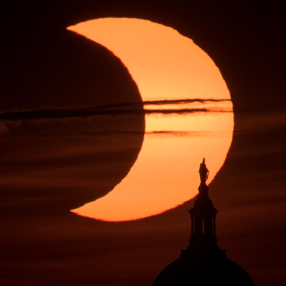 The sun rises behind the Statue of Freedom on top of the United States Capitol Building (NASA via Getty Images)