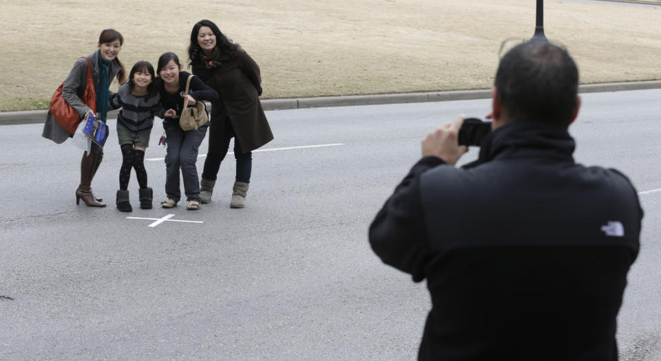 In this Friday, Jan. 25, 2013 file photo, tourists pose for a photo on the spot where John F. Kennedy was shot in Dealey Plaza in Dallas. (AP Photo/LM Otero)