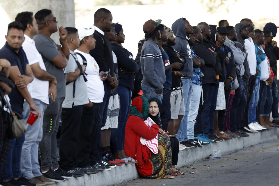 FILE - In this Tuesday, July 16, 2019, file photo, people wait to apply for asylum in the United States along the border in Tijuana, Mexico. In its efforts to remake the U.S. immigration system, the Trump administration has often stumbled over an obscure law that governs how administrative policies are made. Its latest test is a mammoth proposal to severely limit access to asylum, which invited nearly 80,000 public comments before the Wednesday, July 15, 2020, deadline to offer feedback. (AP Photo/Gregory Bull, File)