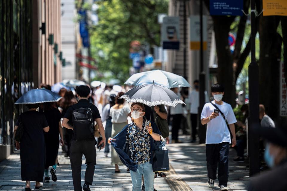 People walk in the summer heat in Tokyo's Omotesando area on July 16, 2021.