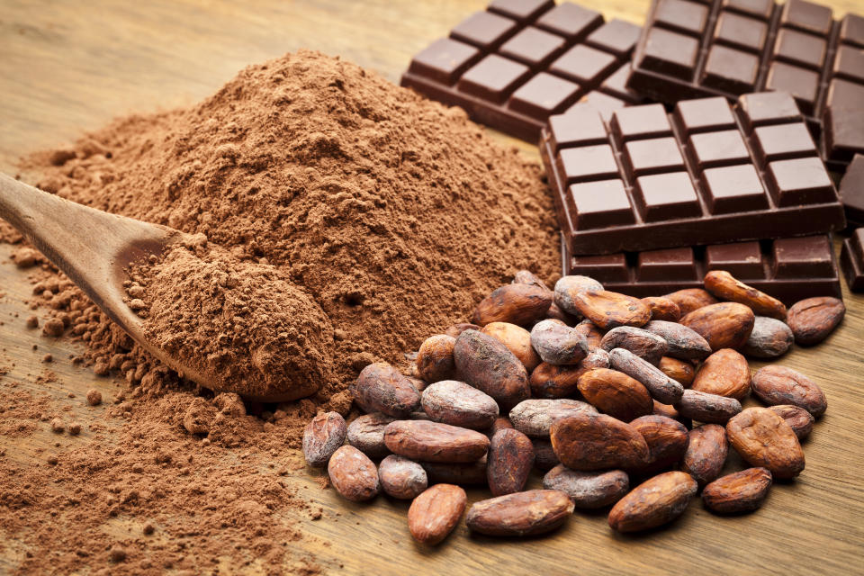 Cocoa Beans and Cocoa Powder with Chocolate Bars on Wood Table. (fcafotodigital / Getty Images stock)