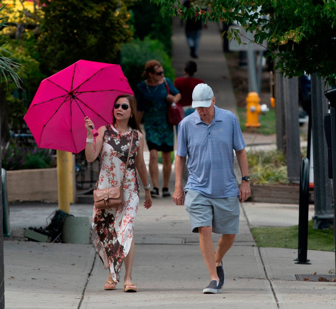 A couple walks down Glenwood Avenue in the Glenwood South district at 5pm Friday afternoon, July 21, 2023.