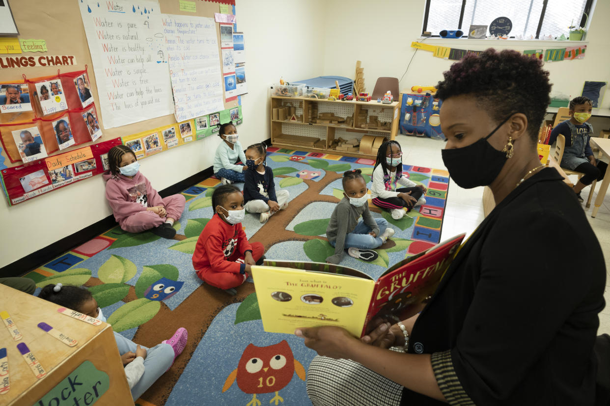 Parent Melissa Jean reads a book to a pre-K class, all wearing face masks.