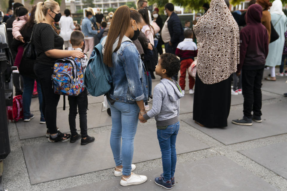 Children and relatives, wearing face masks to fight against the spread of the coronavirus, wait to enter the Heembeek primary school during the first school day of classes in Brussels, Tuesday, Sept. 1, 2020. From Belgium to Russia, France to Hungary, tens of millions of kids return to school on Tuesday. While it can be a joyous time for youngsters, many parents and teachers are more than uneasy how that will fuel the continent's daily infection rates. (AP Photo/Francisco Seco)