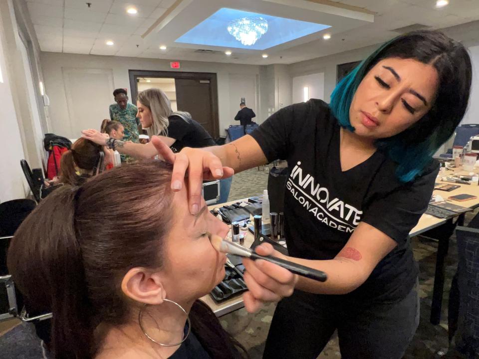 Alyssa Ortiz, a student at Innovate Salon Academy in South Plainfield, applies makeup to Szalay's face before the fashion show.