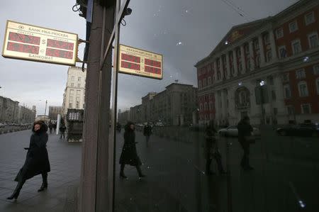 A woman walks along a street past a board showing currency exchange rates in Moscow December 3, 2014. REUTERS/Maxim Zmeyev