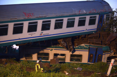 A fire fighter stands next to the twisted wreckage of a train that plowed into a truck last night in Caluso near Turin, Italy, May 24, 2018. REUTERS/Massimo Pinca