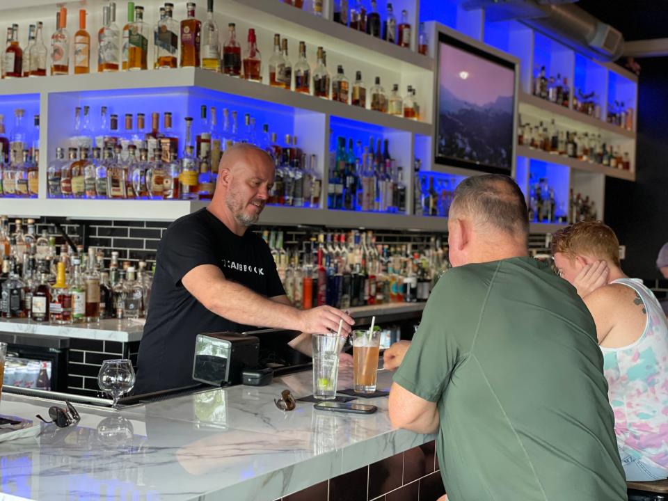 Blackbook bar manager Neil Goetz serves patrons drinks in Palm Springs, Calif., Monday, Aug. 8, 2022.