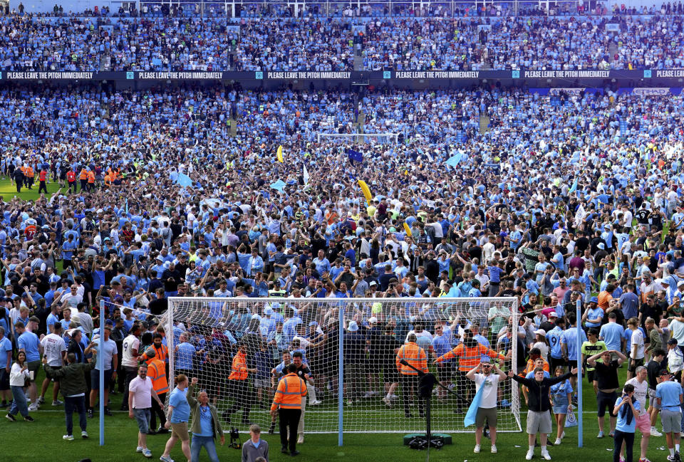 Manchester City fans invade the pitch as they celebrate their English Premier League title win at the end of the English Premier League soccer match between Manchester City and Chelsea at the Etihad Stadium in Manchester, England, Sunday, May 21, 2023. (Martin Rickett/PA via AP)