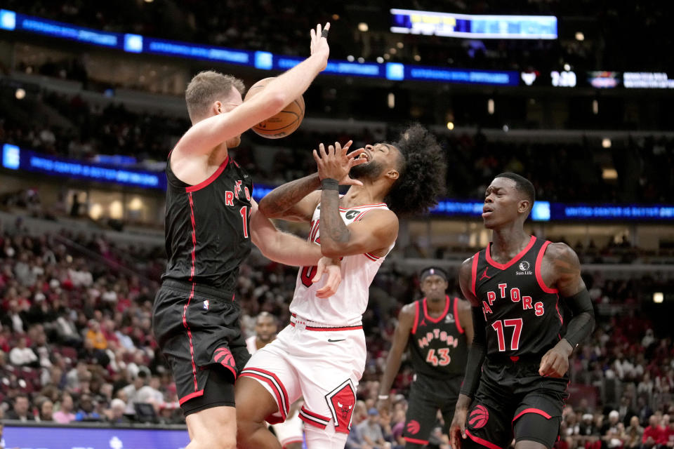 Toronto Raptors' Jakob Poeltl, left, fouls Chicago Bulls' Coby White, front center, as Raptors' Dennis Schroder (17) watches during the first half of an NBA basketball game Friday, Oct. 27, 2023, in Chicago. (AP Photo/Charles Rex Arbogast)