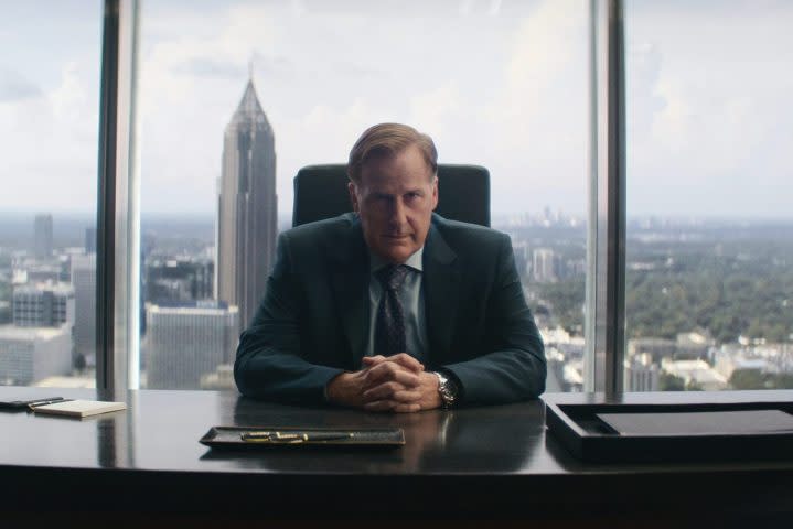 A man sits a desk in front of a window.