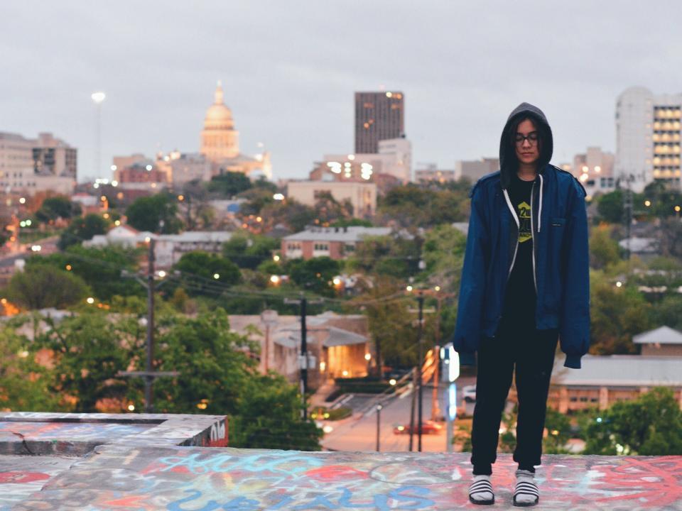 The author stands on top of a graffiti park in Austin with the skyline behind her