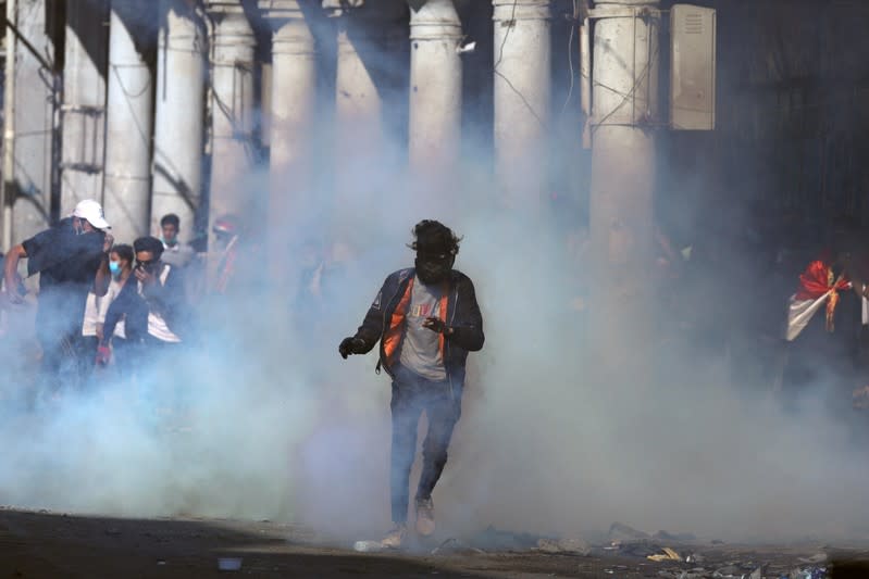 An Iraqi demonstrator runs from tear gas during the ongoing anti-government protests in Baghdad