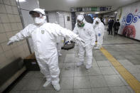 Workers wearing protective gears help clean each other's suits after disinfecting as a precaution against the coronavirus at a subway station in Seoul, South Korea, Friday, Feb. 21, 2020. South Korea on Friday declared a "special management zone" around a southeastern city where a surging viral outbreak, largely linked to a church in Daegu, threatens to overwhelm the region's health system. (AP Photo/Ahn Young-joon)