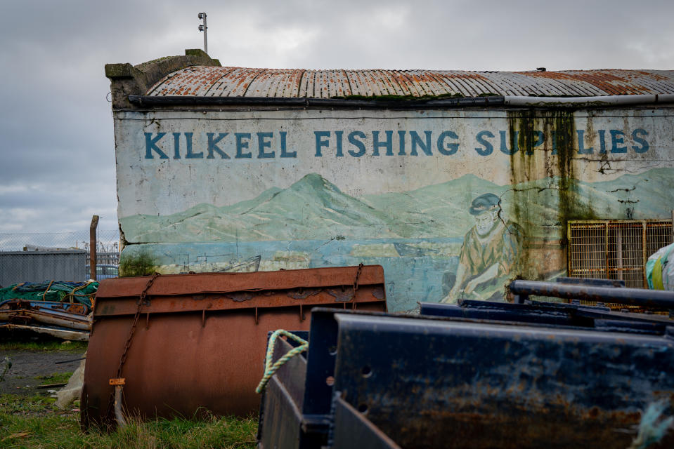 In this Tuesday, Jan. 28, 2020 photo, old fishing equipment rusts away in front of old hand painted advertisement for fishing supplies at Kilkeel harbour in Northern Ireland. The United Kingdom and the European Union are parting ways on Friday and one of the first issues to address is what will happen to the fishing grounds they shared. (AP Photo/David Keyton)