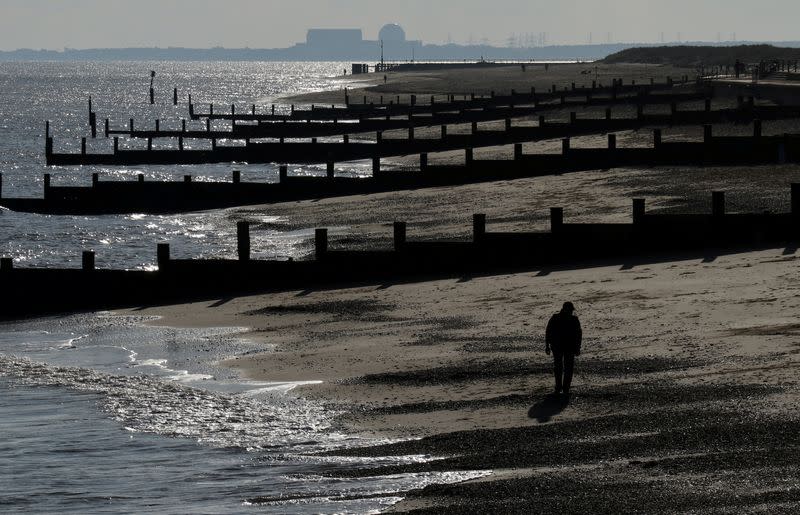 FILE PHOTO: A man walks along the beach along the Suffolk coast near in Southwold, Britain