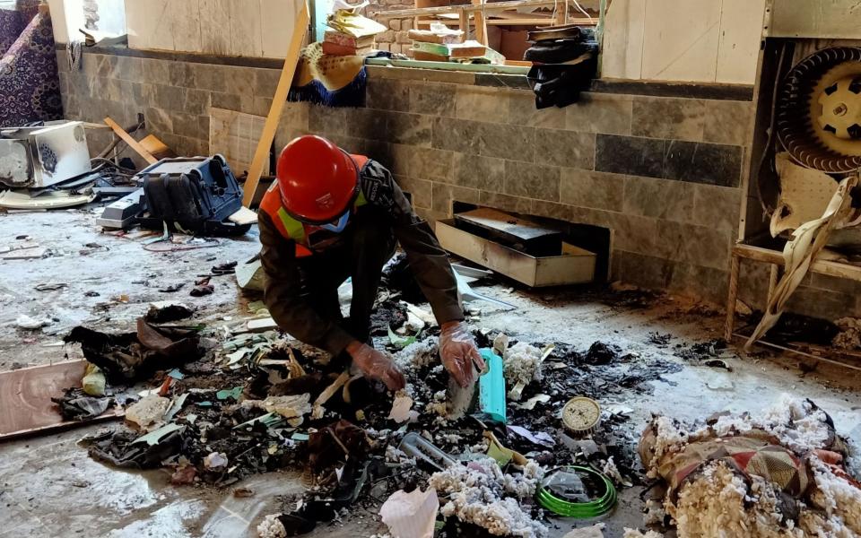 A rescue worker examines remains at the site of a blast at a religious school in Peshawar - AFP