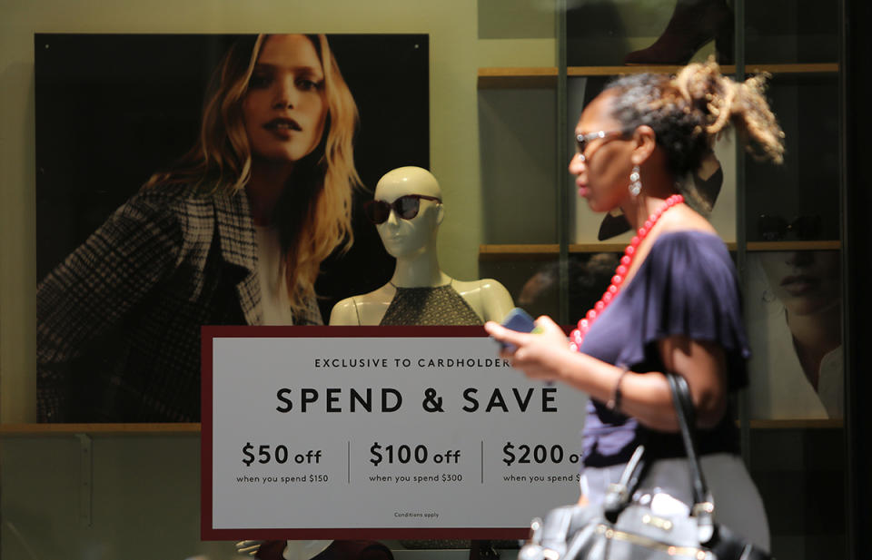 Woman walking past clothing store ahead of Black Friday sales.