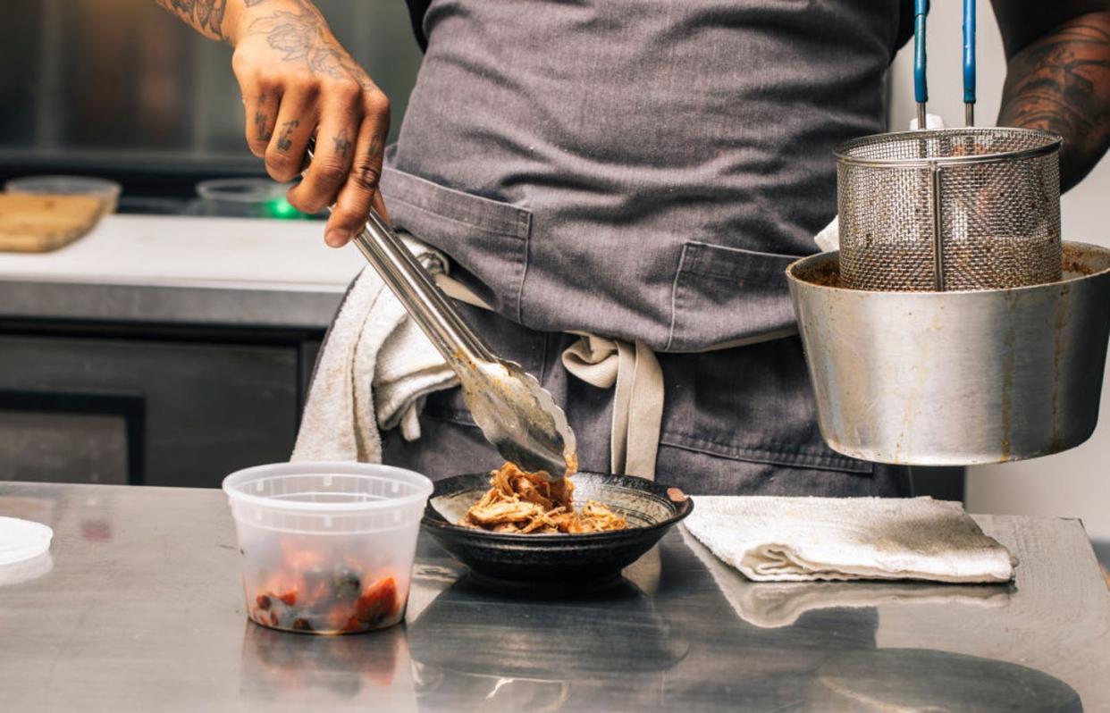 <span class="caption">The co-founder of a takeout business called The Bussdown plates a dish at the ghost kitchen he cooks out of in Oakland.</span> <span class="attribution"><a class="link " href="https://www.gettyimages.com/detail/news-photo/michael-woods-co-founder-of-pan-african-ghost-kitchen-the-news-photo/1313210547?adppopup=true" rel="nofollow noopener" target="_blank" data-ylk="slk:Stephen Lam/The San Francisco Chronicle via Getty Images;elm:context_link;itc:0;sec:content-canvas">Stephen Lam/The San Francisco Chronicle via Getty Images</a></span>