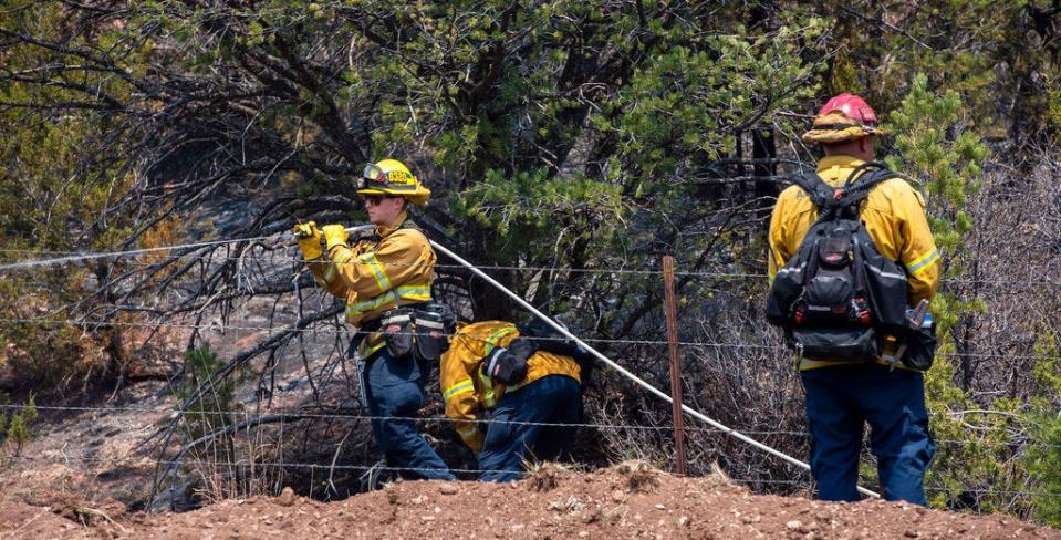 Jeff Franco, left, and other wildland firefighters from Apple Valley, Calif., mop up hot spots along NM 283 near Las Vegas, N.M., Thursday, May 5, 2022. Firefighters are trying to hold the Calf Canyon/Hermit Peak Fire at the road and not let it cross.