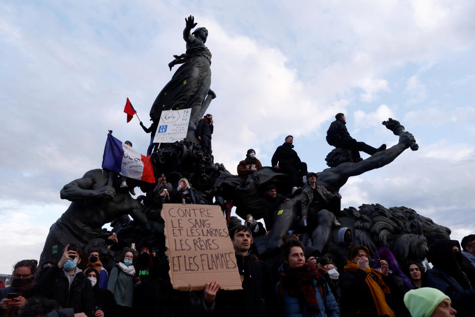 Protesters hold a French national flag as they stand on the statue of the Place de la Nation during a demonstration as part of the tenth day of nationwide strikes and protests against French government's pension reform, in Paris, France, March 28, 2023. The slogan reads 