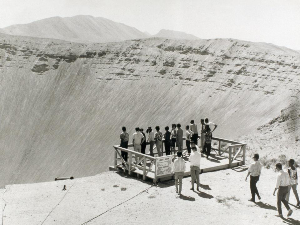 Onlookers are looking at the crater created by a nuclear explosion in Nevada.