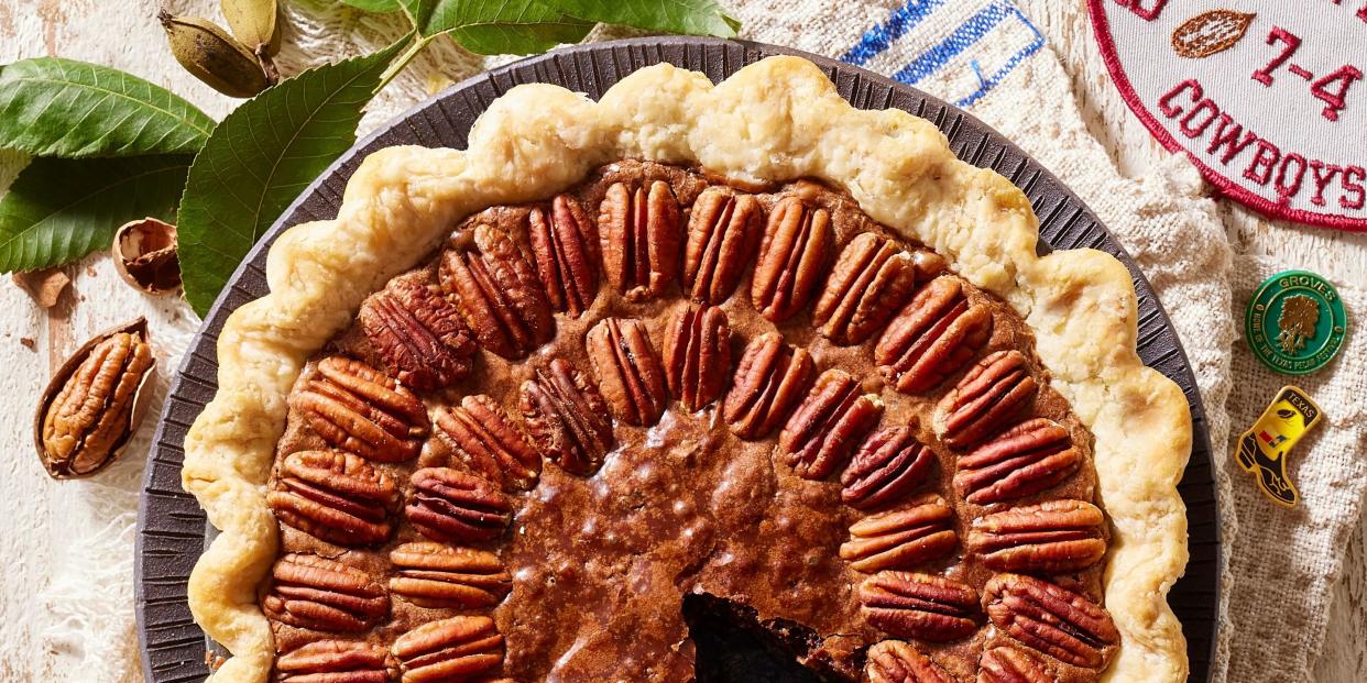 pecan brownie pie in a metal pie plate with a basket of pecans