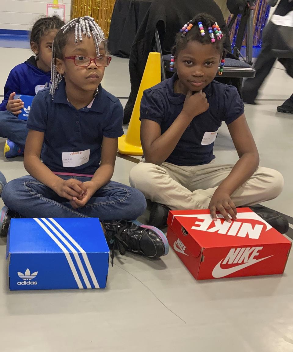 Two students at Miles Intermediate Elementary School in Atlanta sit with new shoes they received from Mercedes-Benz USA, as a part of their Season to Shine holiday program, on Wednesday, Dec. 7, 2022. (AP Photo/Sharon Johnson)