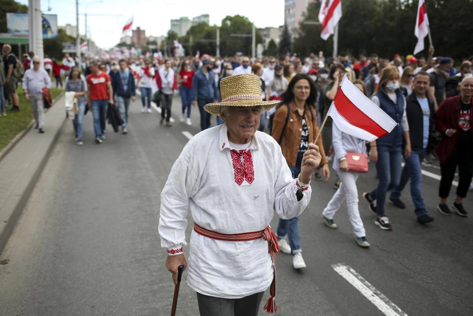 An elderly protester with an old Belarusian national flag attends a Belarusian opposition supporters' rally protesting the official presidential election results in Minsk, Belarus, Sunday, Sept. 13, 2020. Protests calling for the Belarusian president's resignation have broken out daily since the Aug. 9 presidential election that officials say handed him a sixth term in office. (TUT.by via AP)