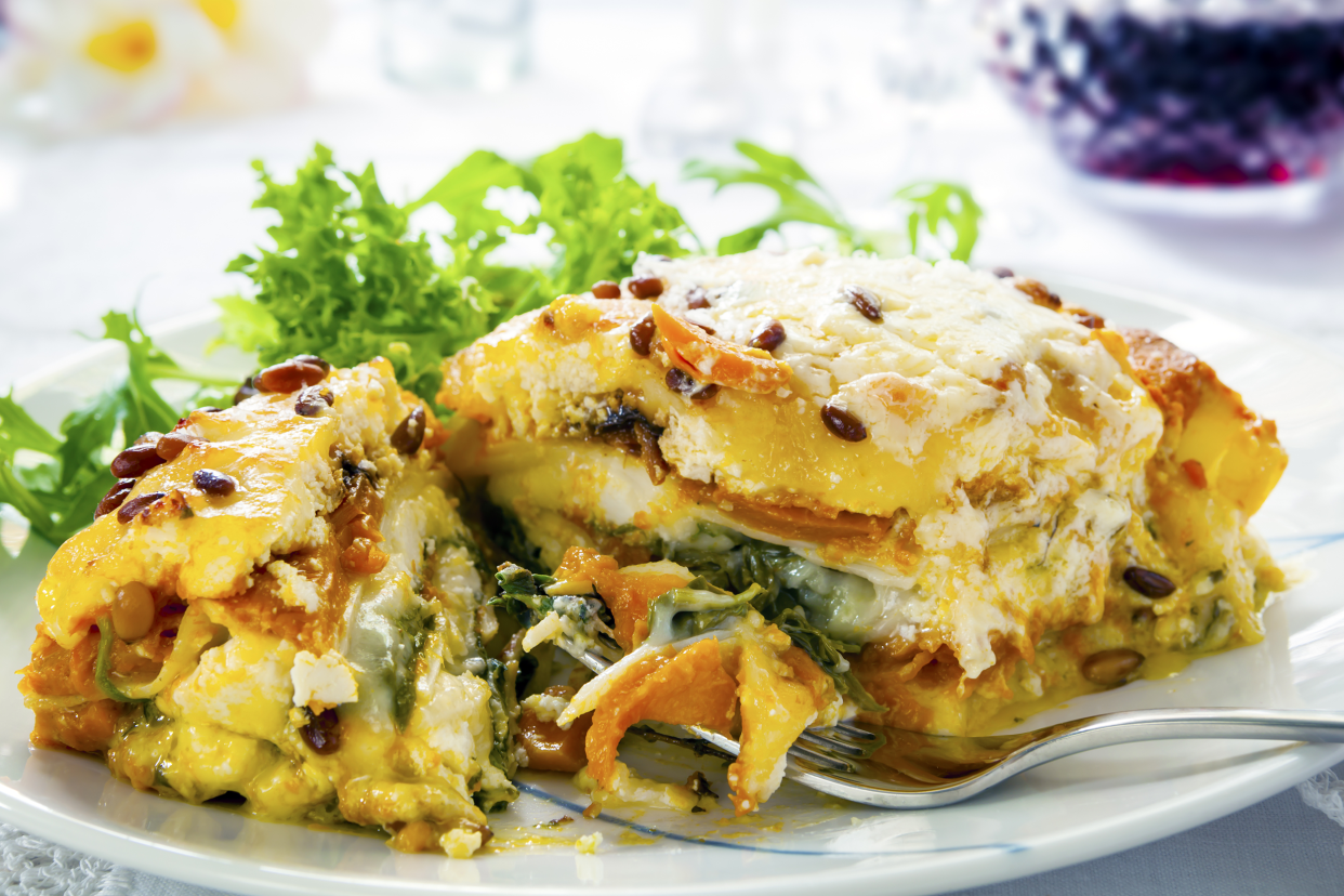 Focus on vegetarian Thanksgiving lasagna on a white plate with a fork with a blurred background