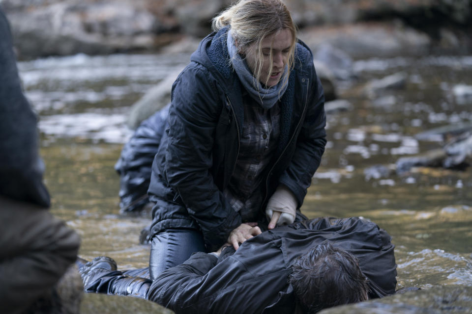 Kate Winslet in character as Mare Sheehan handcuffing a man in a river on the set of the Binge TV series Mare of Easttown