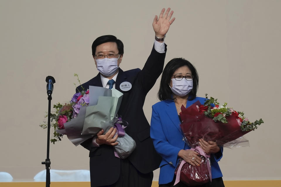 John Lee (izquierda), el exfuncionario número 2 de Hong Kong y el único candidato para el puesto más alto de la ciudad, celebra con su esposa luego de declararse ganador de las elecciones de jefe ejecutivo en Hong Kong, el domingo 8 de mayo de 2022. (AP Foto/Kin Cheung)