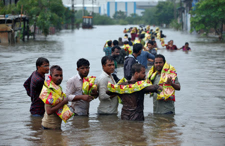 People carry packets of snacks after receiving them from civil defence volunteers in a flooded neighbourhood after heavy rains in Ahmedabad, July 27, 2017. REUTERS/Amit Dave