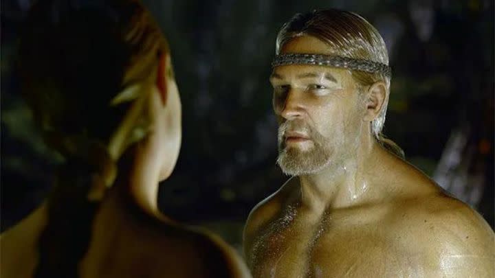 A shirtless man looks at a woman in Beowulf.