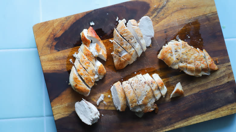 Sliced roasted chicken breasts on cutting board