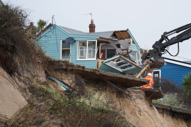 Demolition workers tear down the first of five clifftop homes in the village of Hemsby which has been hit by coastal erosion.