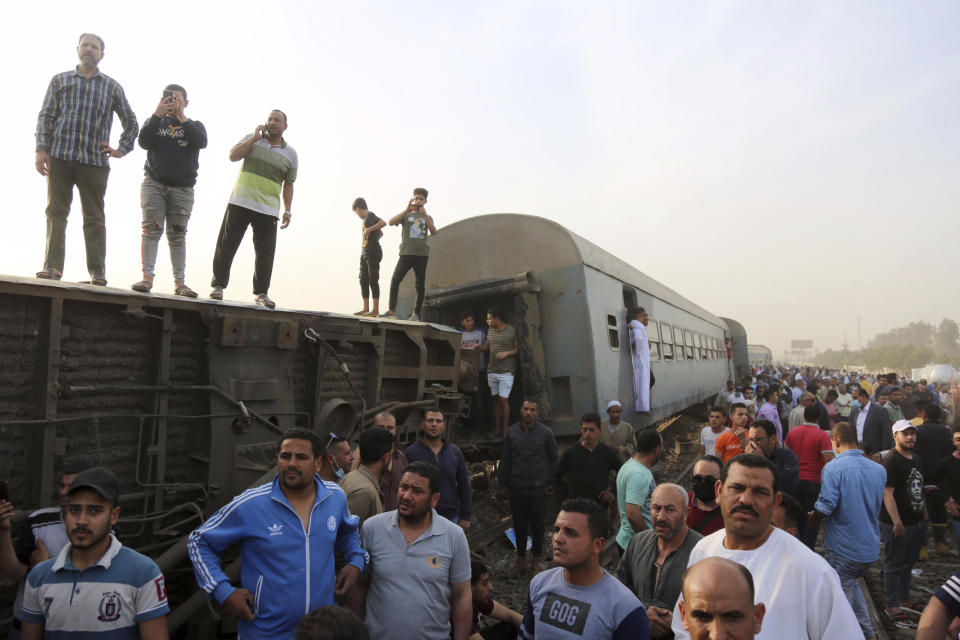 People gather at the site where a passenger train derailed injuring at least 100 people, in Banha, Qalyubia province, Egypt, Sunday, April 18, 2021. At least eight train wagons ran off the railway, the provincial governor's office said in a statement. (AP Photo/Fadel Dawood)